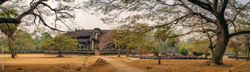 Ancient ruins of temple complex Angkor Wat surrounded by old tropical trees, Siem Reap, Cambodia. Angkor was the capital of Khmer Empire for over 600 years. Ancient ruins of temple complex Angkor Wat surrounded by old tropical trees, Siem Reap, Cambodia. Angkor was the capital of Khmer Empire for over 600 years.
