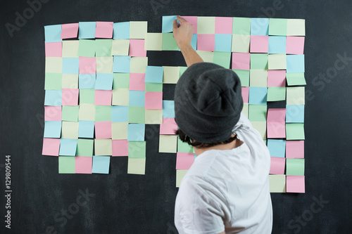 Man sticking sticky notes on the wall photo