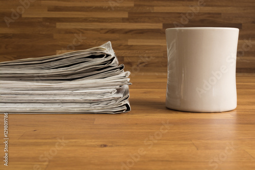 Ein Stapel Zeitungen und eine Tasse auf einem Holztisch photo