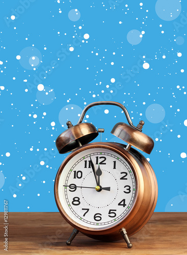 Bronze retro alarm clock at twelve o'clock amid flying snow.