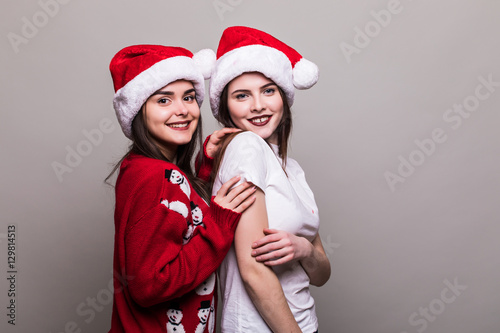 Two girls in Santa hat isolated on grey background