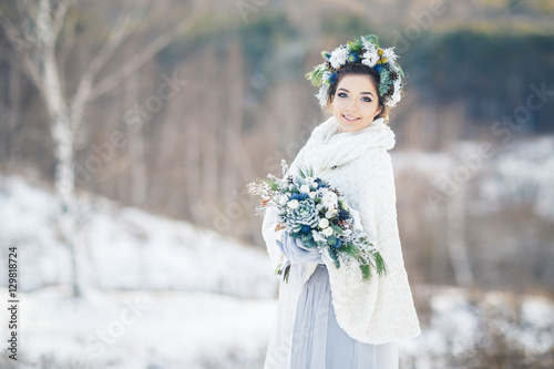 Bride with bouquet looking at the camera. Bride in the Park in winter.
