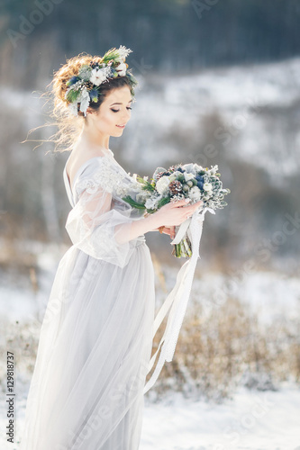 Beautiful bride admiring wedding bouquet. Winter wedding. Winter wedding bouquet.