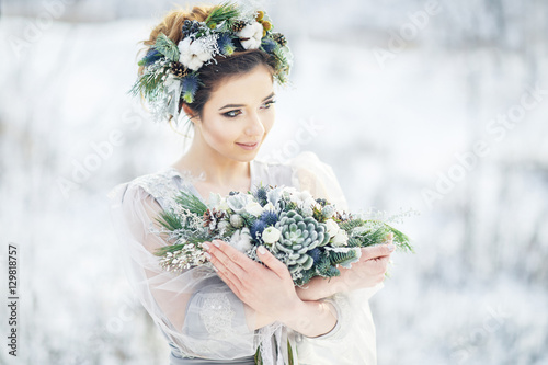 Portrait of a beautiful bride with a bouquet. Wedding ceremony in winter.