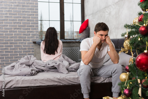 Young man is leaning on his hands while sitting sadly on bed, gi photo