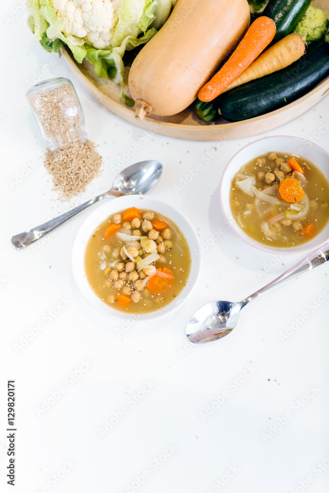 Two bowls with soup and chickpeas on white background.