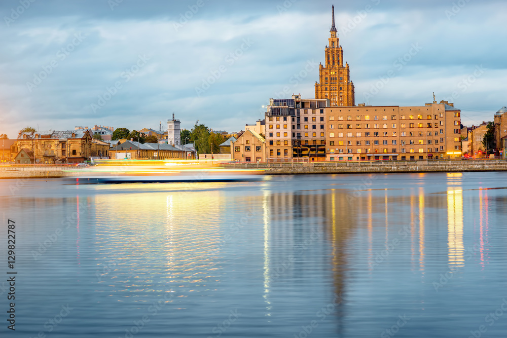 Night view on the illuminated riverside with science academy building in Riga, Latvia