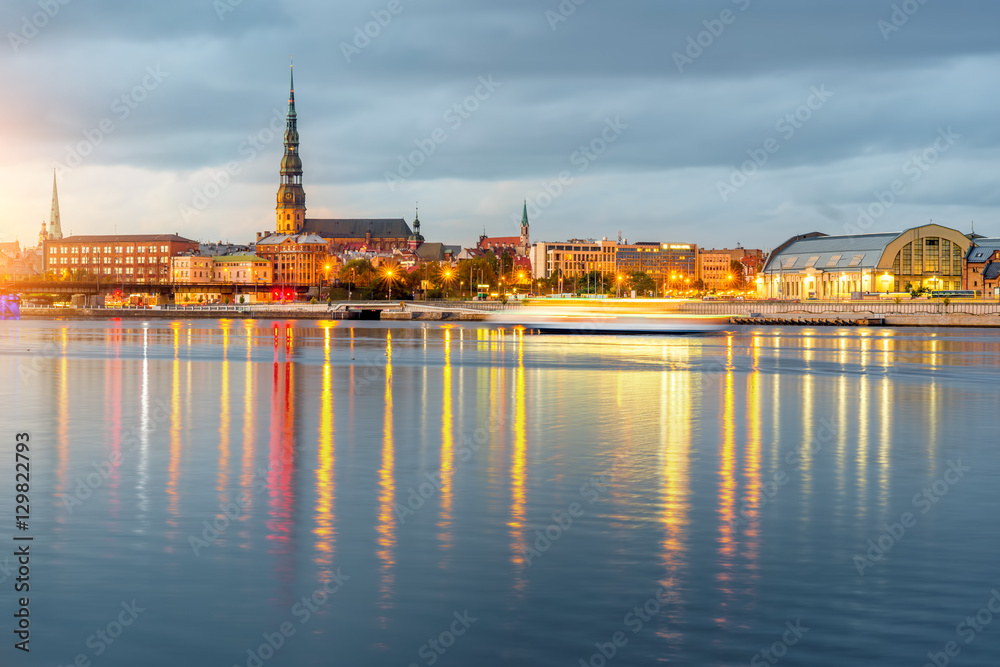 Night view on the illuminated riverside with reflection on the river in Riga, Latvia