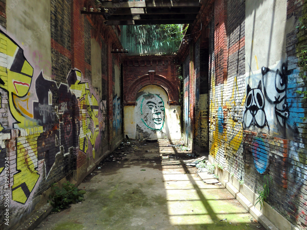 Jesus face graffiti down abandoned brick corridor