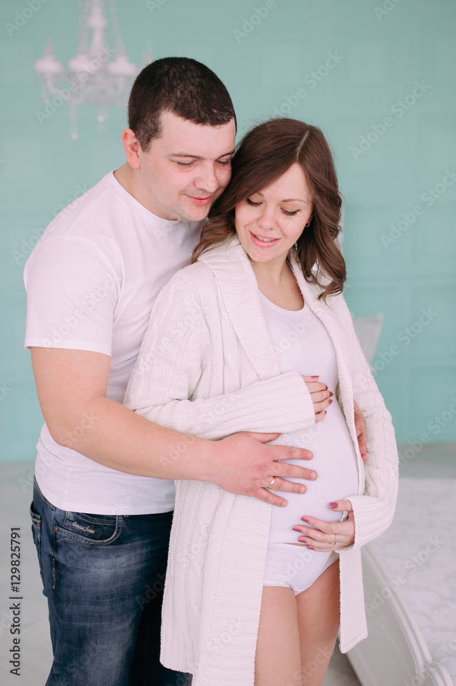 Family waiting for baby's birth. A pregnant woman and her husband wearing white clothing Family waiting for baby's birth. A pregnant woman and her husband wearing white clothing