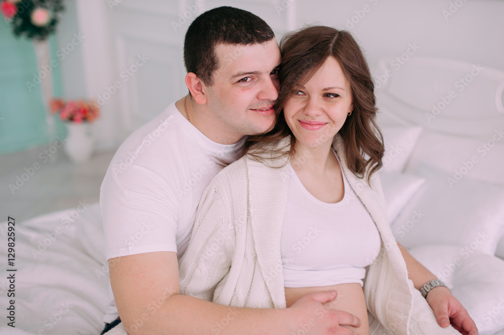 Family waiting for baby's birth. A pregnant woman and her husband wearing white clothing Family waiting for baby's birth. A pregnant woman and her husband wearing white clothing
