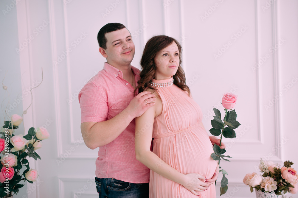Family waiting for baby's birth. A pregnant woman and her husband wearing white clothing Family waiting for baby's birth. A pregnant woman and her husband wearing white clothing
