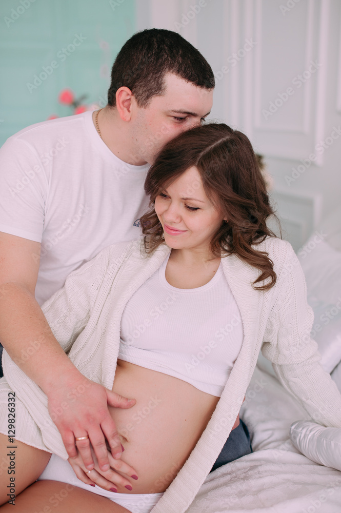 Family waiting for baby's birth. A pregnant woman and her husband wearing white clothing Family waiting for baby's birth. A pregnant woman and her husband wearing white clothing
