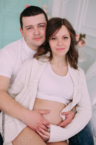 Family waiting for baby's birth. A pregnant woman and her husband wearing white clothing