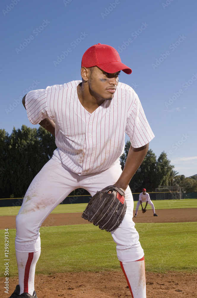 Obraz premium Young baseball pitcher playing on field with team mate in the background