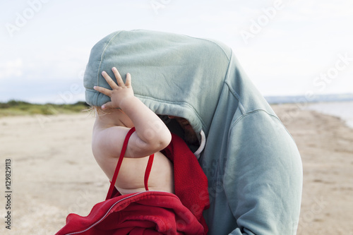 Sweden, Halland, Mellbystrand, Girl (2-3) hiding in father´s hooded shirt photo