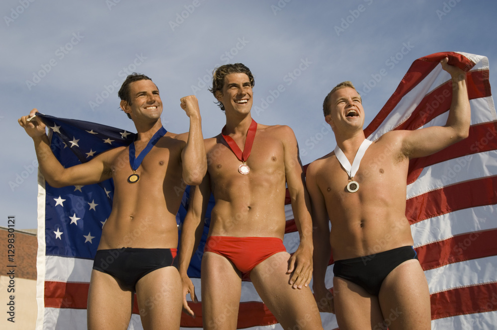 Victorious male athletes cheering up while holding an American flag