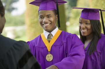 Closeup of a graduate looking at cropped dean with female friend