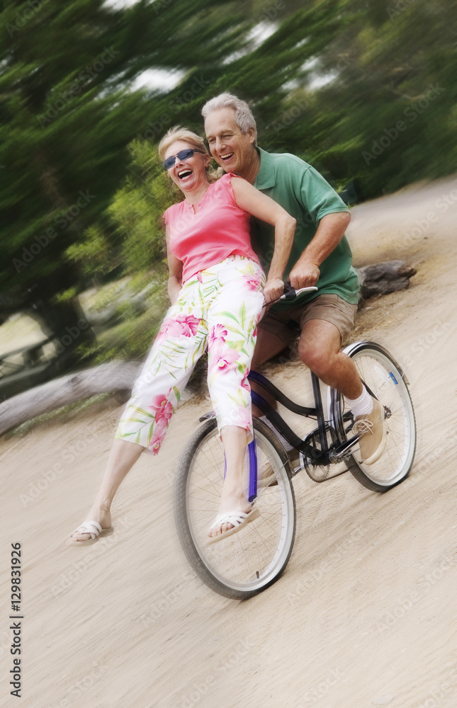Fototapeta premium Full length of excited man riding bicycle while woman sitting on handlebar