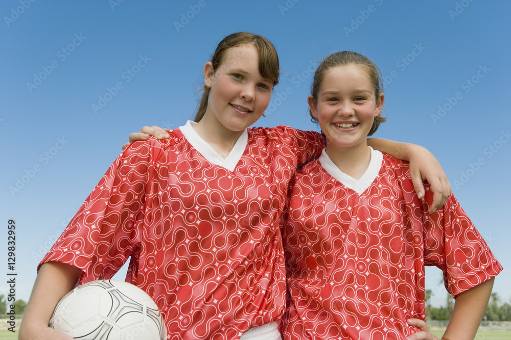 Φωτογραφία Portrait of happy two young girls dressed to play football against clear sky
