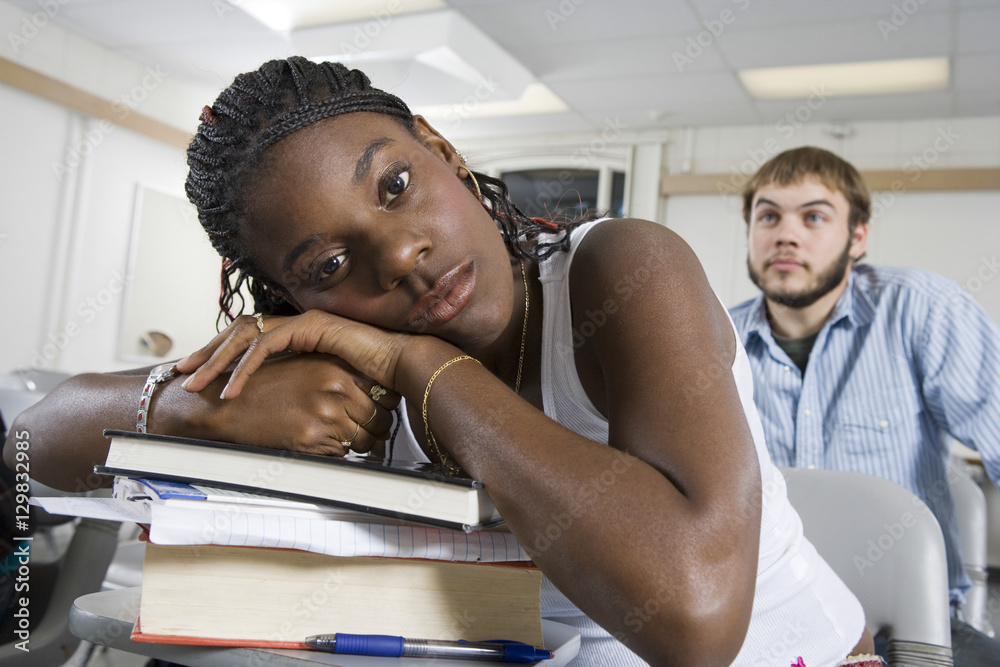 Φωτογραφία Closeup portrait of bored young African American student resting on stack of boo