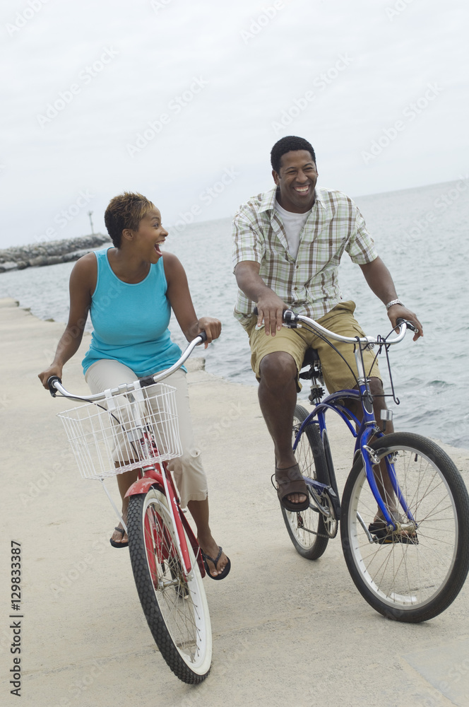 Happy African American couple riding bicycle at beach Happy African American couple riding bicycle at beach