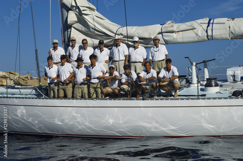 Sailing crew posing for a group portrait on board against clear blue sky