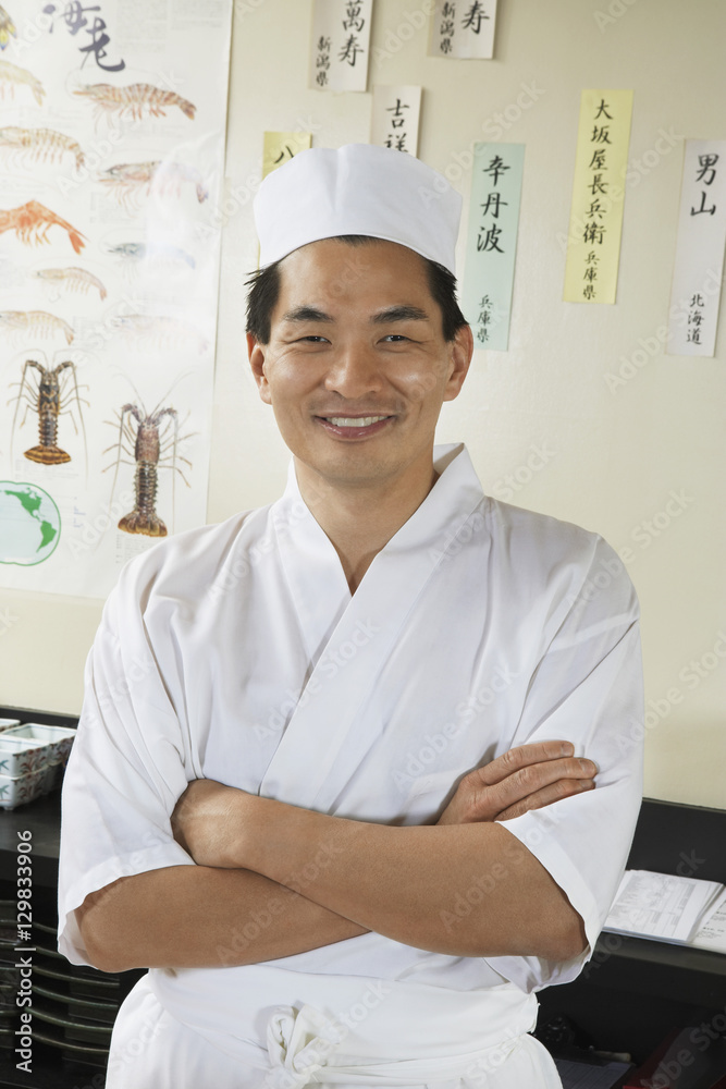 Portrait of a happy Asian chef standing with arms folded at restaurant Portrait of a happy Asian chef standing with arms folded at restaurant