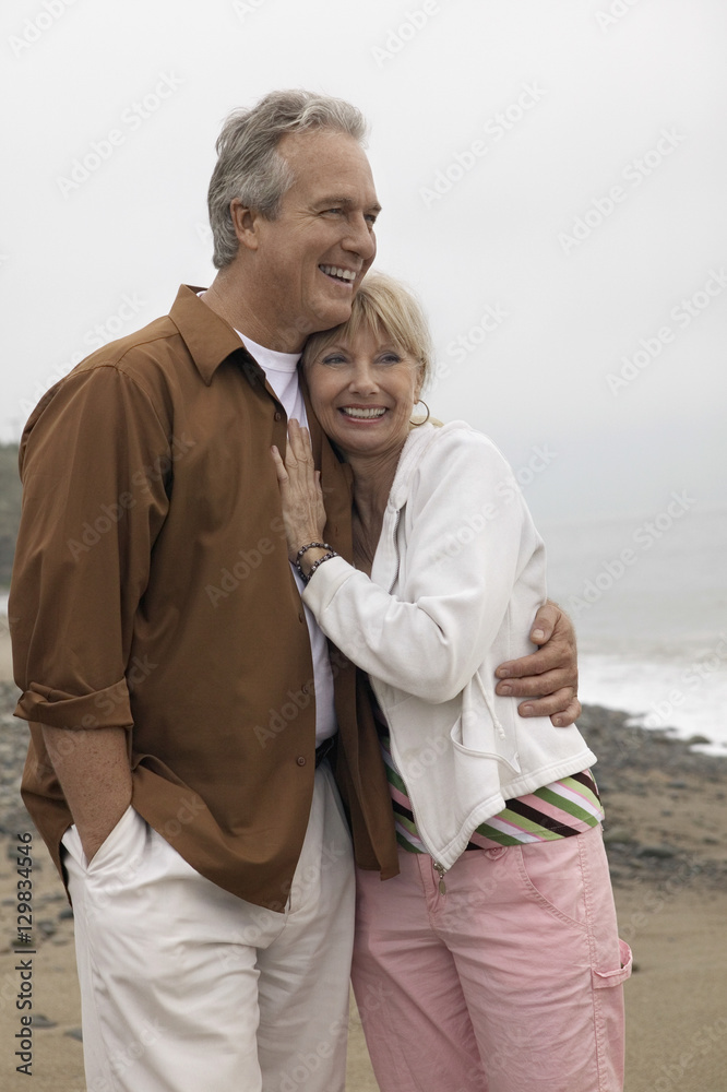Obraz premium Romantic couple looking away while embracing each other on beach
