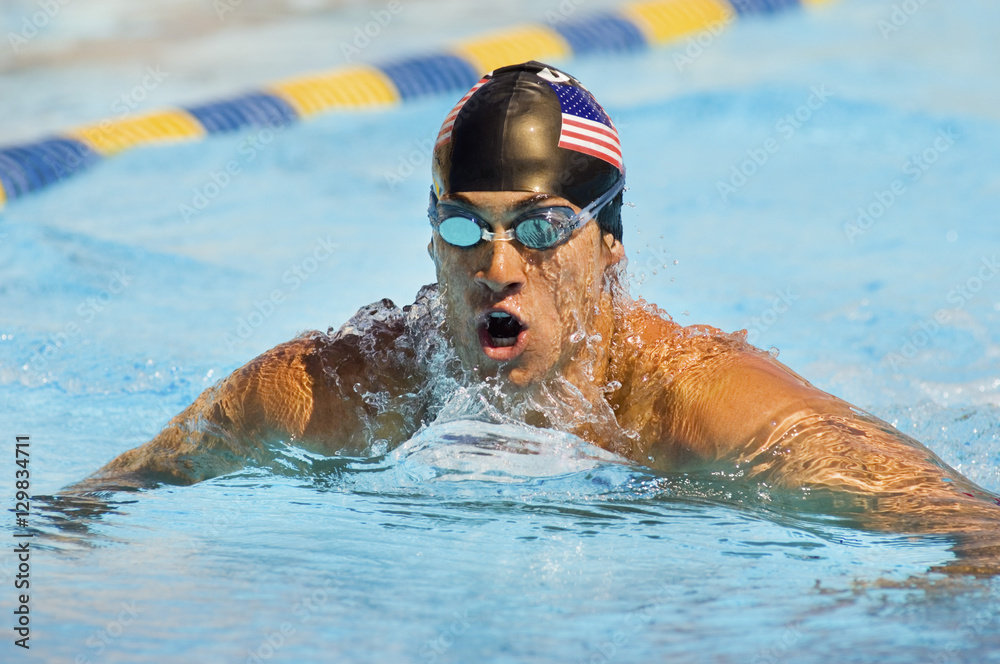 Male professional swimmer wearing goggles and cap swimming in a pool competition
