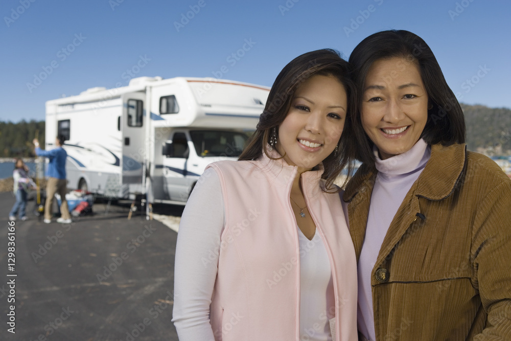 Mother and teenage daughter standing outside of RV at lake Mother and teenage daughter standing outside of RV at lake