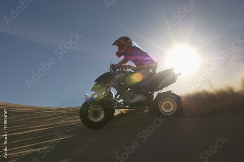 Young man riding quadbike in desert