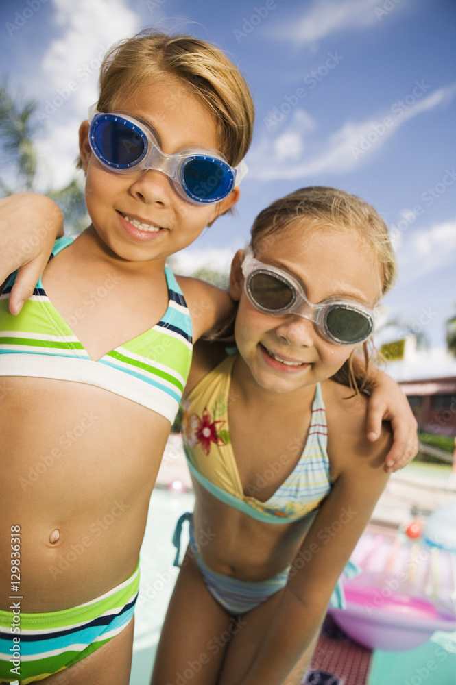 Closeup portrait of two smiling girls with arms around wearing swim goggles Closeup portrait of two smiling girls with arms around wearing swim goggles