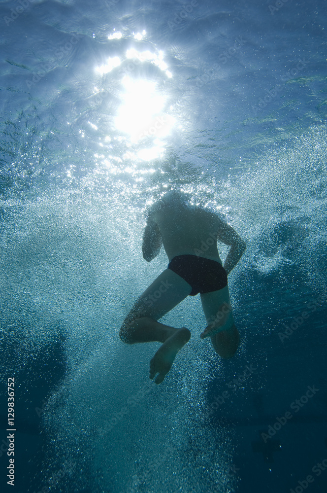 Low angle view of a male swimmer holding breath underwater