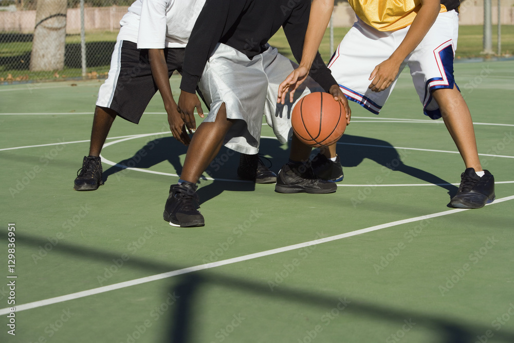 Naklejka premium Low section of three men playing basketball
