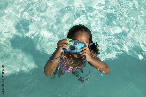 Girl (5-6) Using Waterproof Camera in Swimming Pool overhead view. photo