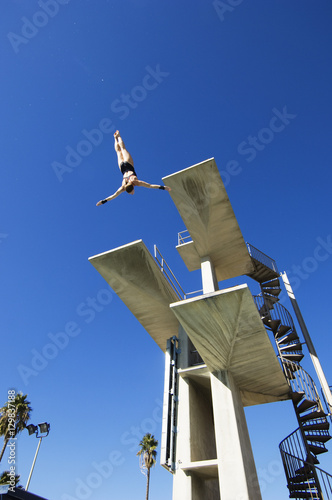 Papier peint Low angle view of a male swimmer diving in midair from the springboard