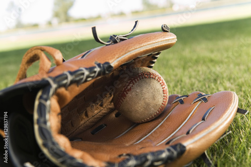 Extreme closeup of an old baseball glove and ball on the field