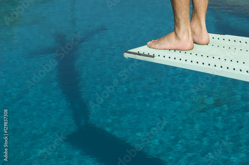 Low section view of a male diver ready for a dive standing at the edge of the springboard