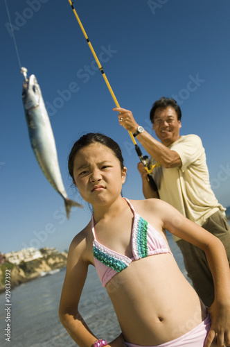 Girl unhappy with her father's catch on beach © moodboard