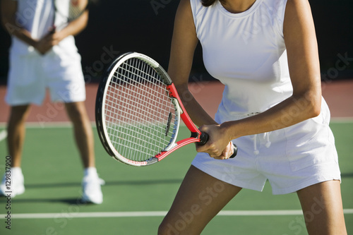 Midsection of mixed doubles tennis players on court with focus on woman © moodboard