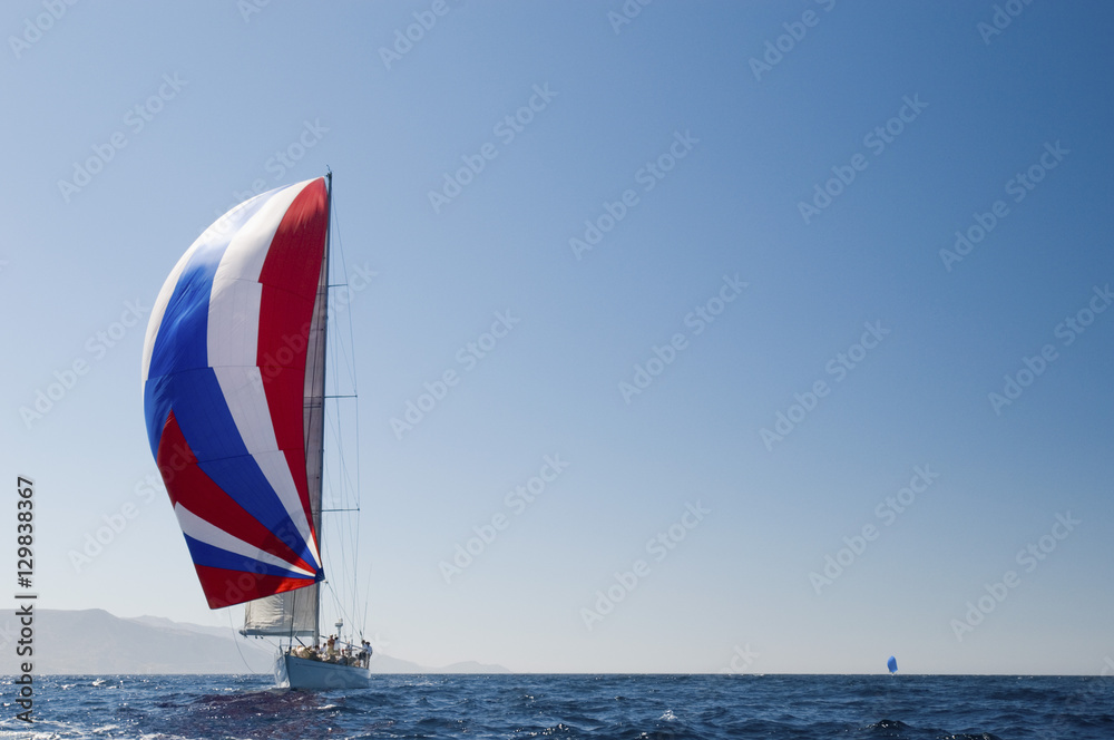 Obraz na plátně Yacht in the blue ocean with full sail against the clear sky