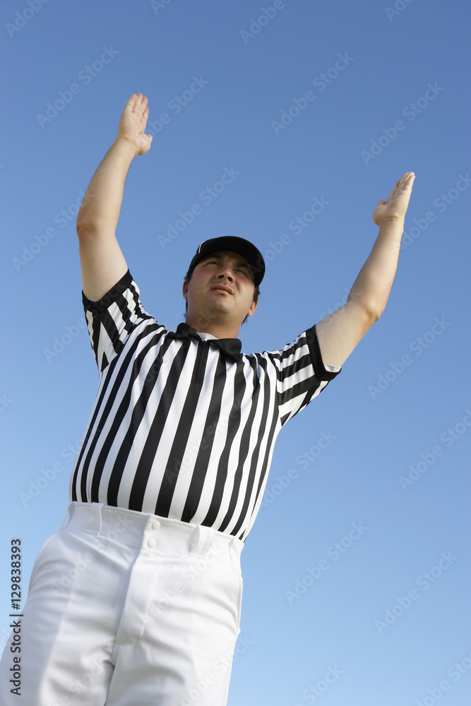 Low angle view of referee gesturing homerun against clear sky Low angle view of referee gesturing homerun against clear sky