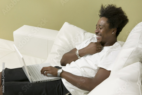 Young man on sofa using laptop side view
