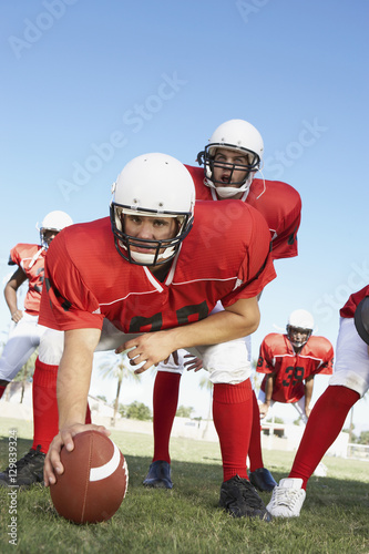 Rugby player placing the ball on field to start the game with teammates in background