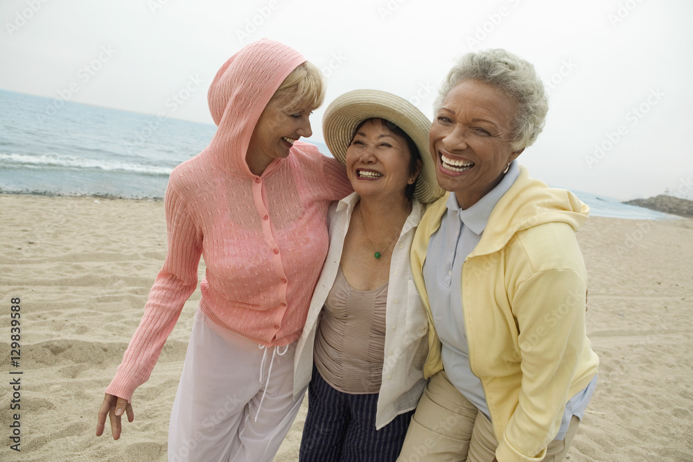 Fototapeta premium Portret szczęśliwi w średnim wieku żeńscy przyjaciele cieszy się wakacje przy plażą