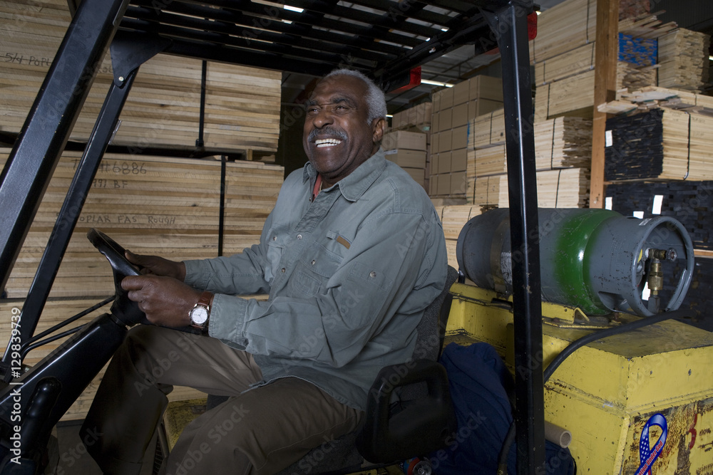 Happy senior warehouse worker sitting in forklift at warehouse Happy senior warehouse worker sitting in forklift at warehouse