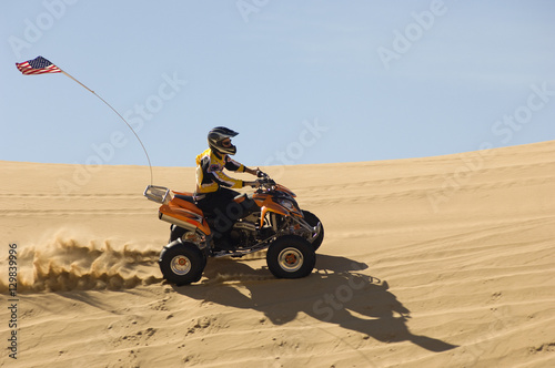 Side view of young man riding quad bike in desert