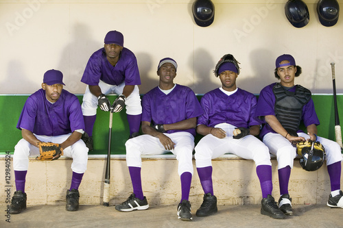 Cuadro en lienzo Tired baseball players sitting side by side in dugout