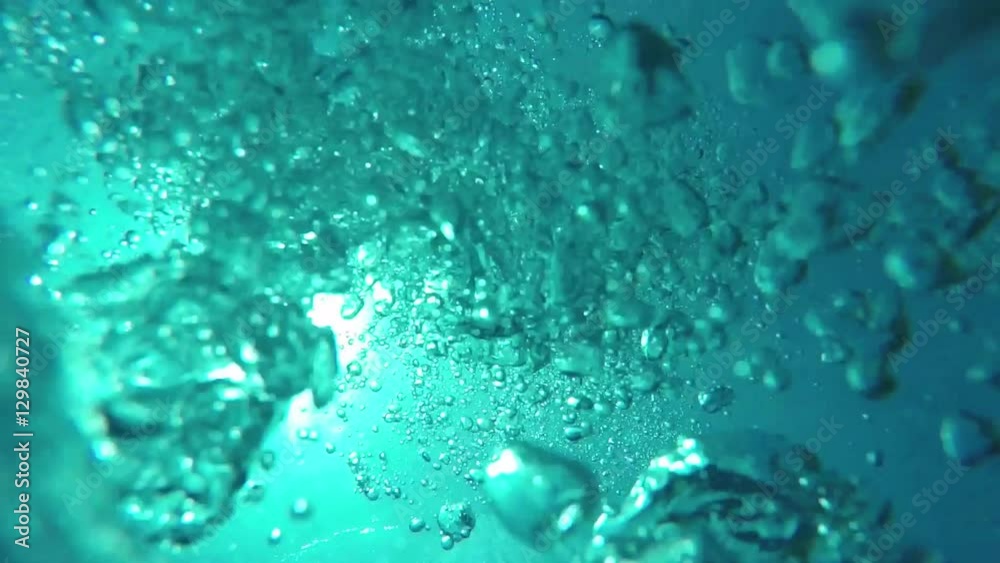 UNDERWATER MACRO:  Manny big air bubbles rising up to the smooth ocean surface  